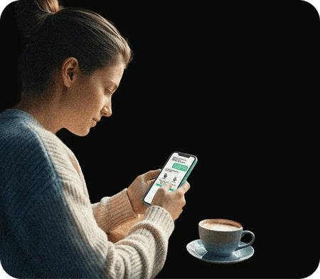 Femme utilisant un smartphone pour consulter une application, assise à côté d'une tasse de café sur une table, fond noir